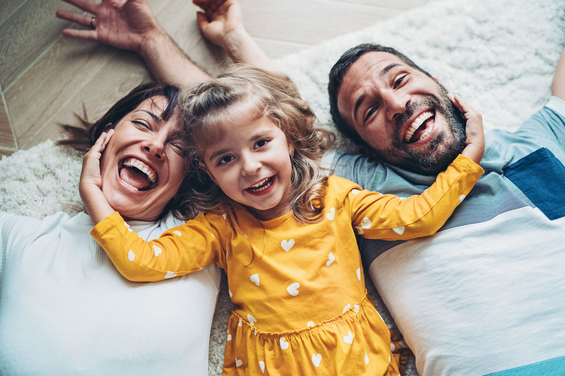 Mother and Father with daughter smiling and laughing on the floor