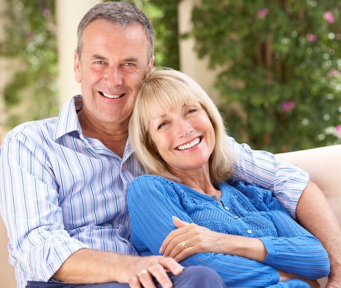 An senior couple sitting together on a couch smiling